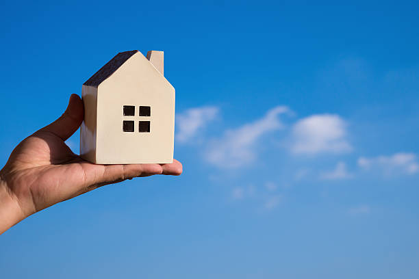 istock hand holding a house model and a blue sky 598949690