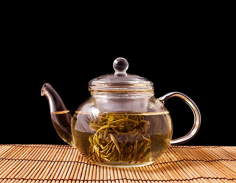 Green tea Jasmine Pearls(Mo Li Long Zhu) in the glass teapot on black background