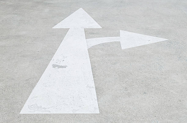 istock Closeup white painted arrow sign on cement street 598954464