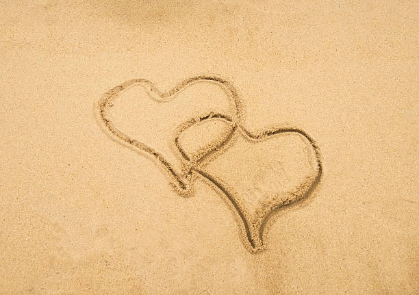 istock two hearts in sand on a beautiful beach 598958904