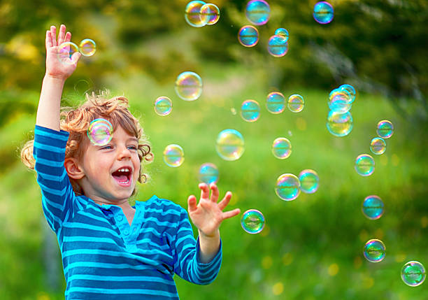 niño y las burbujas de jabón  - bubble wand bubble child playful fotografías e imágenes de stock