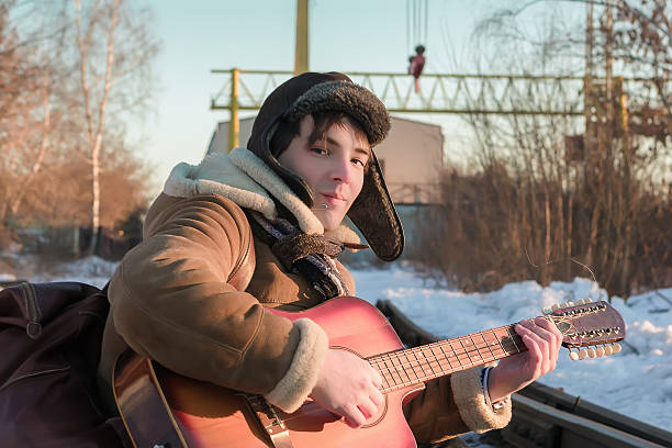 istock Guy On Railway Tracks In Winter Playing Guitar 598962548