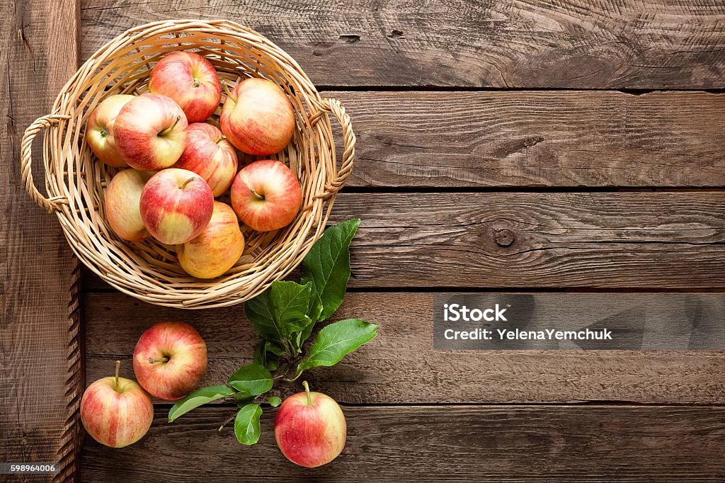 fresh apples in wicker basket on wooden table Apple - Fruit Stock Photo