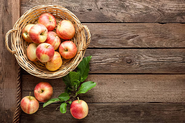 fresh apples in wicker basket on wooden table fresh apples in wicker basket on wooden table basket of fruit stock pictures, royalty-free photos & images