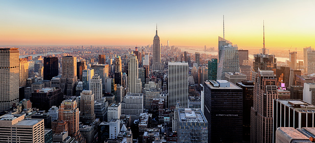 New York City. Manhattan downtown skyline with illuminated Empire State Building and skyscrapers at sunset.