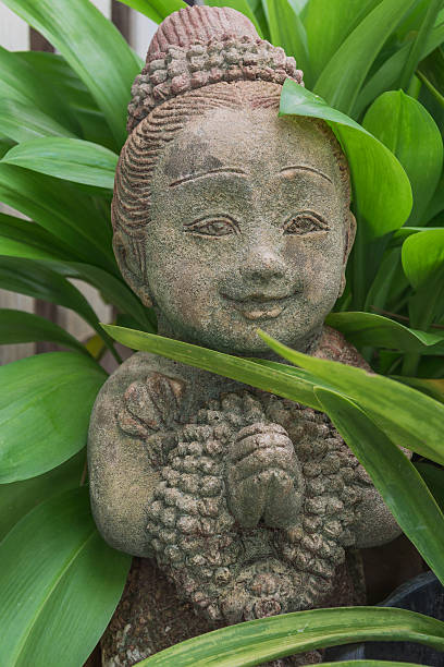 Stone boy statue in a garden with leaves