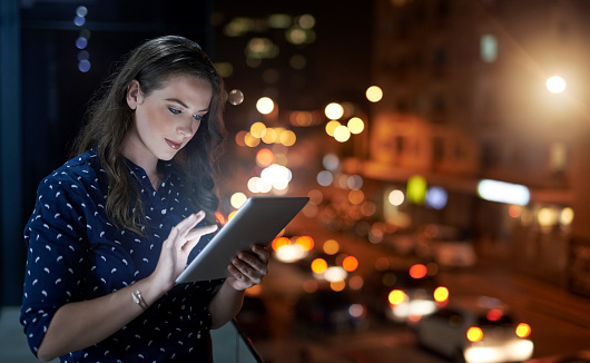 Cropped shot of a young businesswoman working late on a digital tablet outside