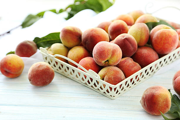 istock Sweet peach fruit in tray on white wooden table 599104566