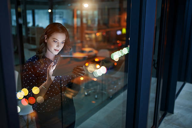 Increasing her efforts to maximise her success Cropped shot of a young businesswoman working late on a digital tablet in an office computer technology people stock pictures, royalty-free photos & images