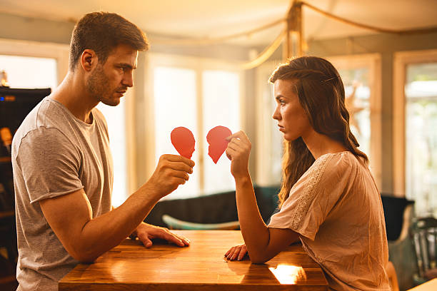 Young couple with broken heart shape looking at each other. stock photo