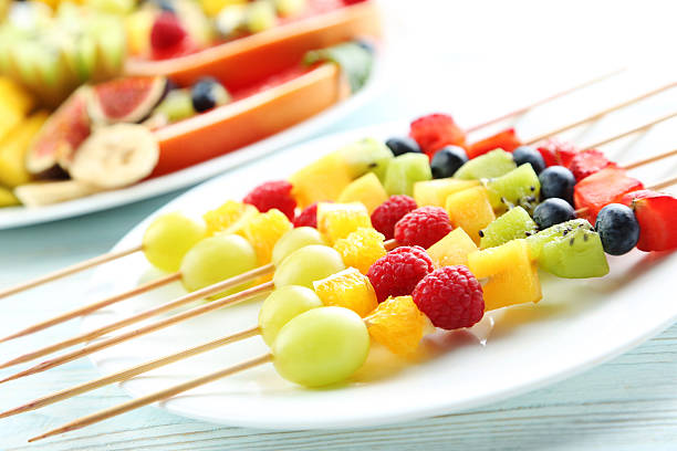istock Fresh fruit on skewers on a white wooden table 599105958
