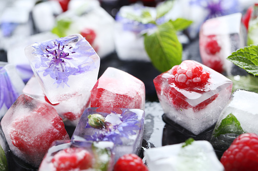 Ice cubes with raspberries and mint leaf on wooden table