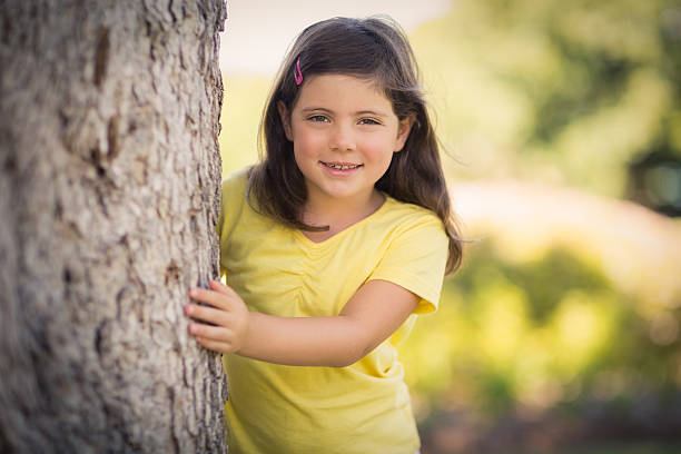 istock Smiling girl hugging  tree trunk in park 599112264