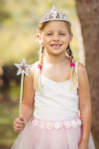 Portrait of young girl pretending to be a fairy in park