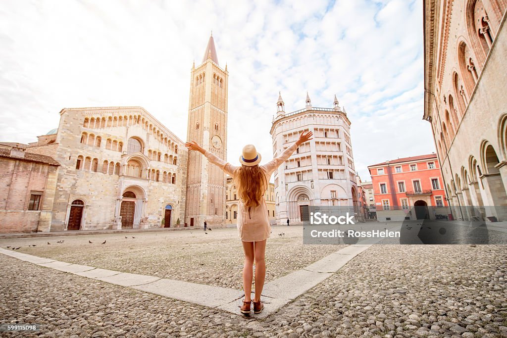 Traveling in Parma town Young female tourist standing back on the central square with cathedral and famous leaning tower on the background in Parma town. Having great vacations in Parma Italy Stock Photo