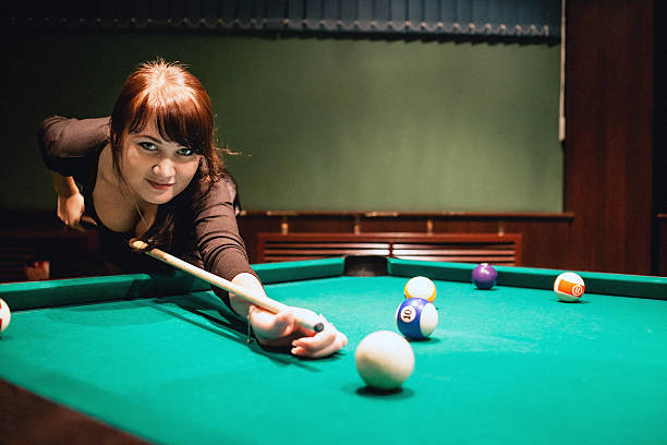 istock Beautiful young busty brunette woman playing billiard on red table 599121380