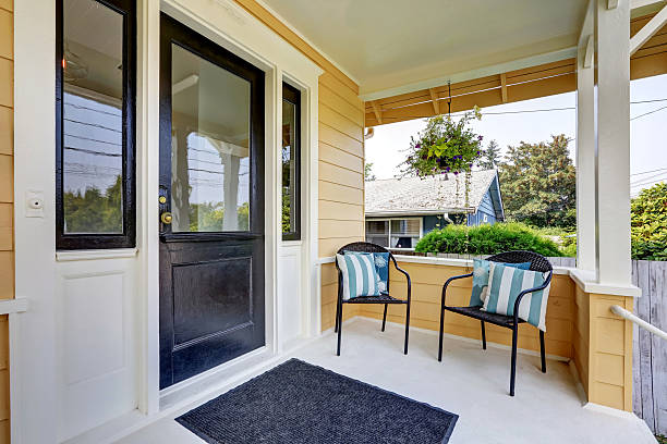istock Covered porch with black front door and two wicker chairs. 599124306