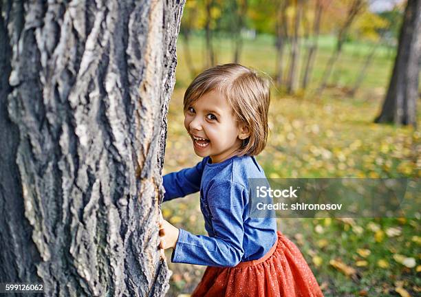 Girl Playing Hide And Seek In Park Stock Photo - Download Image Now - Child, Playful, Playing