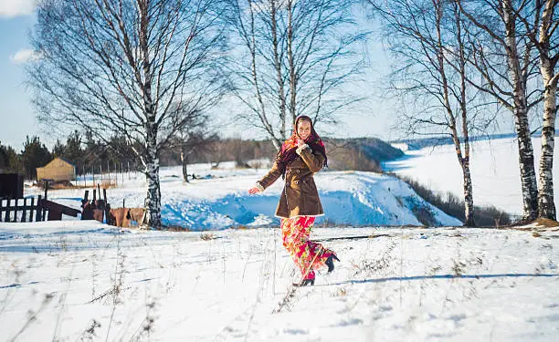 Photo of smiling young beautiful blond woman in russian winter suit runs