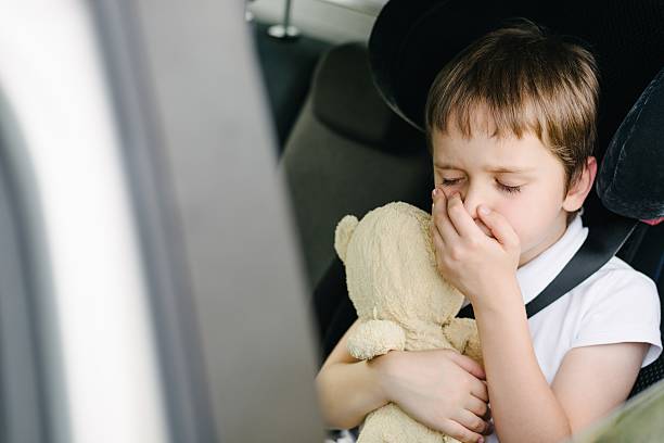 Child suffers from motion sickness in car Seven years old small child in the backseat of a car sitting in children safety car seat covers his mouth with his hand - suffers from motion sickness nausea photos stock pictures, royalty-free photos & images