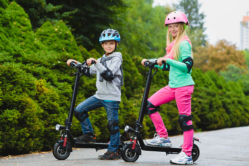 Happy kids standing on electric scooter outdoor.