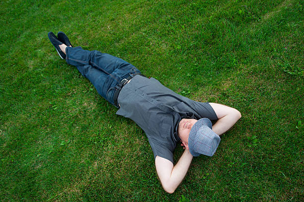istock man lying in a field on green grass with the 599134514