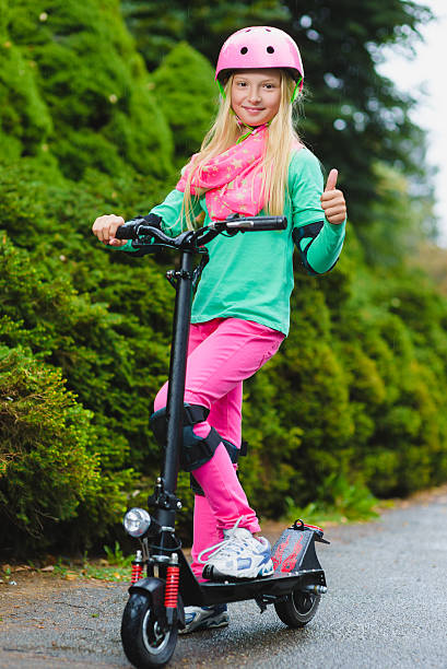 Happy girl standing on electric scooter outdoor stock photo