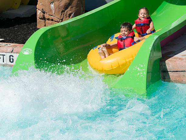 istock Boy and girl sliding into a pool on a raft 599136082