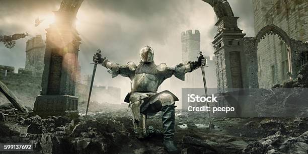 Medieval Knight Kneeling With Sword In Front Of Building Ruin Stock Photo - Download Image Now