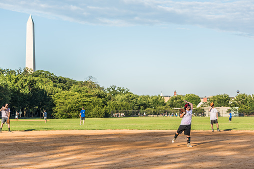 Washington D.C., USA  - August 4, 2016: Happy, smiling people playing baseball on the National Mall with woman pitcher