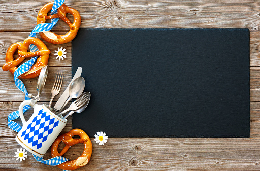 Bavarian pretzels with silverware and beer stein on wooden board. Background for Beer Fest