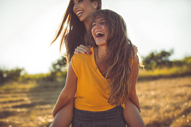 Two smiling girlfriends having fun in piggyback ride