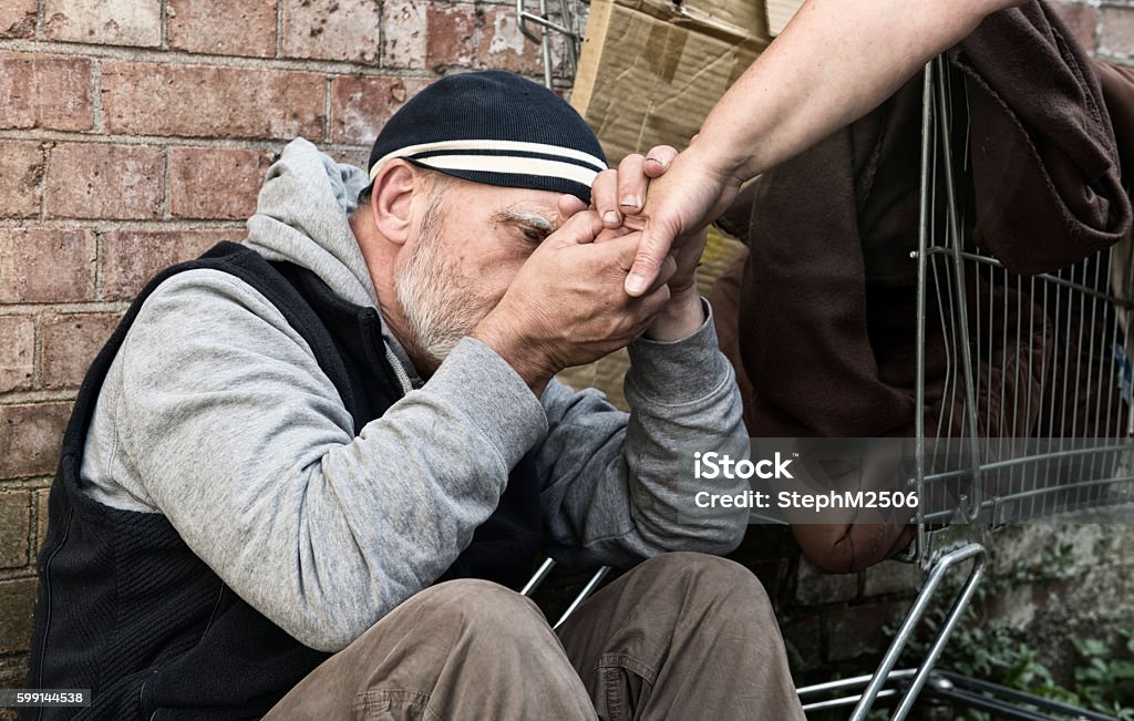 Homeless man taking a woman's hand Homeless man taking an unrecognisable woman's hand Assistance Stock Photo