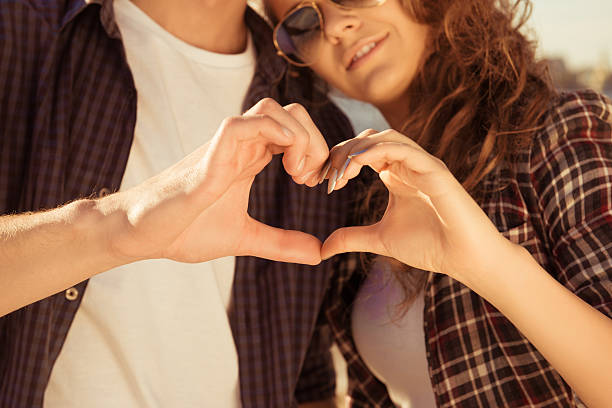 istock romantic couple in love gesturing a heart with fingers 599144638