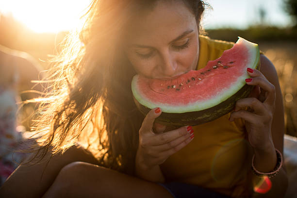 giovane donna che mangia anguria all'aperto - picnic watermelon summer food foto e immagini stock