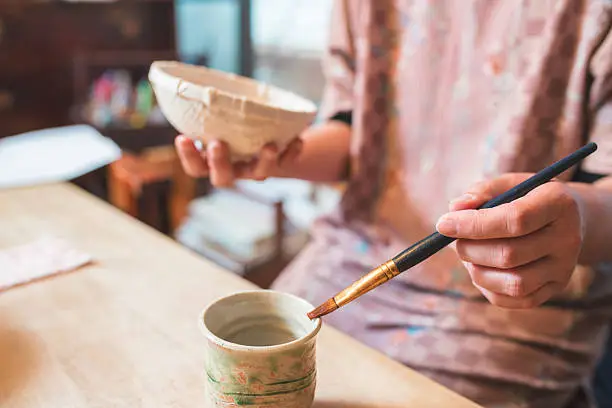 A Traditional Japanese craftswoman adding strips of paper one at a time to create a bowl. Kyoto, Japan. May 2016