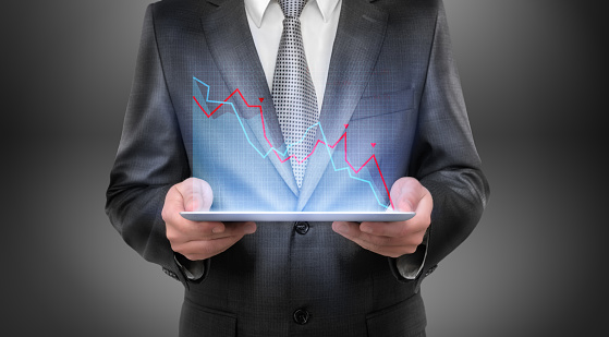 Cropped portrait of a businessman holding tablet with falling diagram above it. Economic and financial crisis. Business recession. Decline and setback.