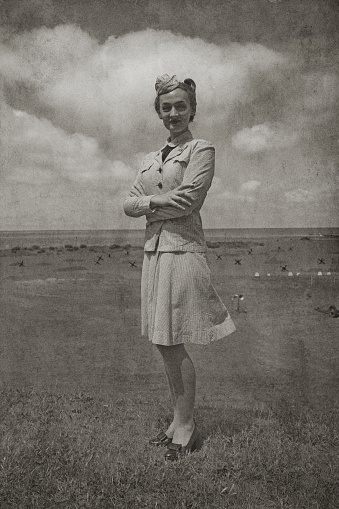 Retro WW2 Navy WAVES  female soldier. Uniform is seersucker summer dress work uniform. Rank is Yeoman 1st Class. Beach background scene includes anti tank obstacles.