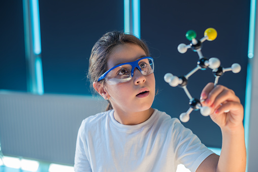 Young scientist looking through a molecular structure model.