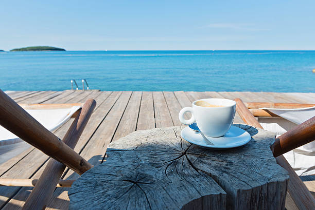Wooden floor with chaise-longues and cup of coffee, Istria, Croatian coast