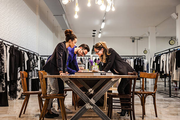 New Business clothing store, team at work on new arrivals New Business clothing store, team at work on new arrivals. Three people team working on documents and new arrivals in the warehouse. clothing design studio stock pictures, royalty-free photos & images