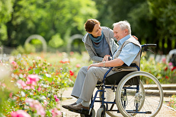 caregiver and senior man on a wheelchair, walking in park - wheelchair disabled senior adult female nurse imagens e fotografias de stock