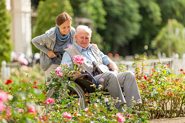 opiekun i starszy człowiek na wózku inwalidzkim spaceru na zewnątrz - nursing home senior adult home caregiver physical therapy zdjęcia i obrazy z banku zdjęć