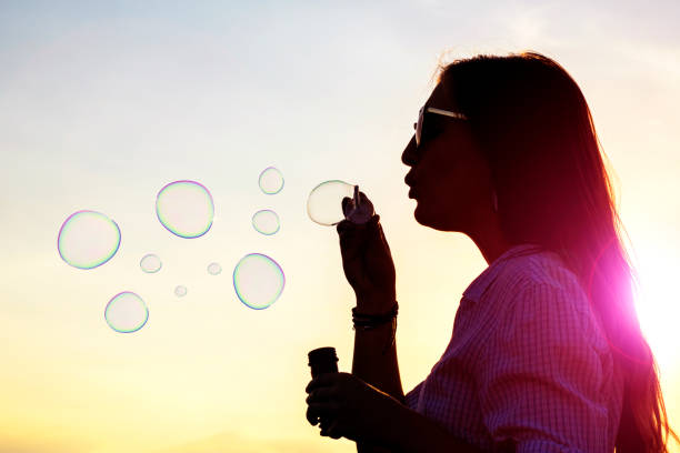 istock Young woman playfully blowing soap bubbles 599267314