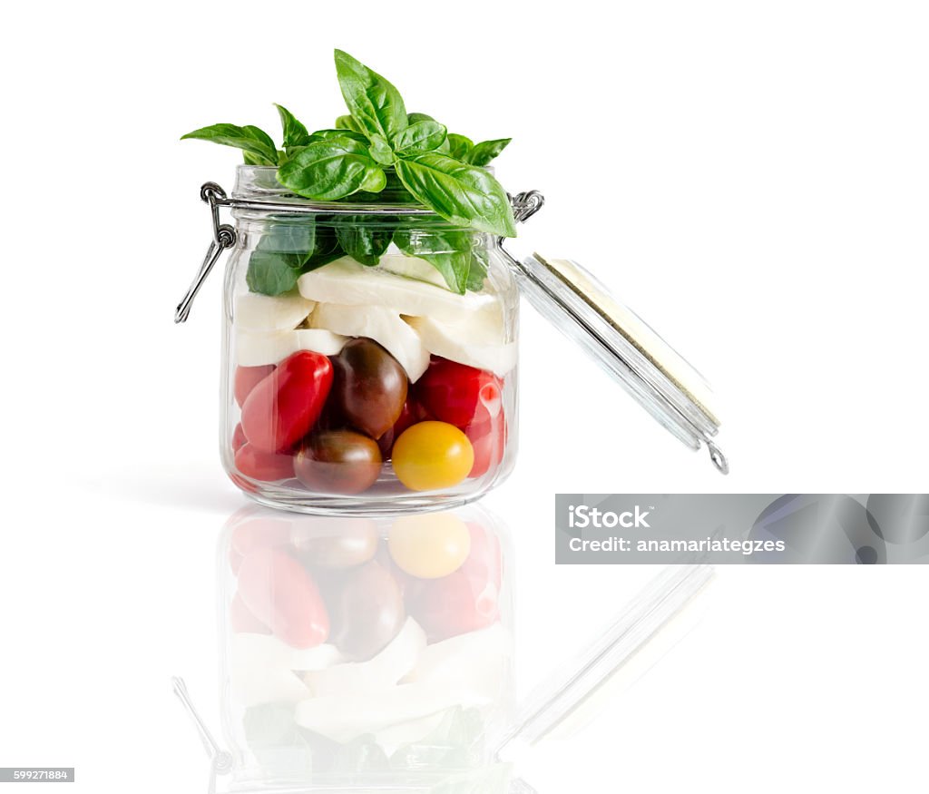 Caprese Salad in an Open Lid Jar Fresh farm style caprese salad in an open lid mason jar isolated on white with reflexion Airtight Stock Photo