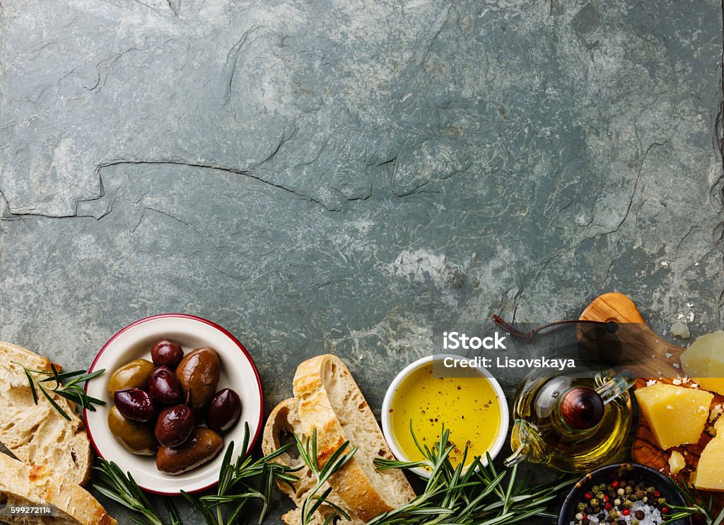 Italian food ingredients background Italian food ingredients background with Sliced bread Ciabatta, parmesan, olive oil, olives and rosemary on gray stone slate Food Stock Photo