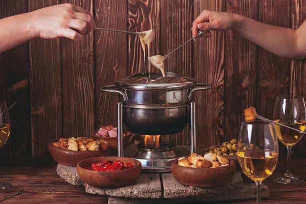 Delicious Cheese Fondue on a fork on a wooden stand