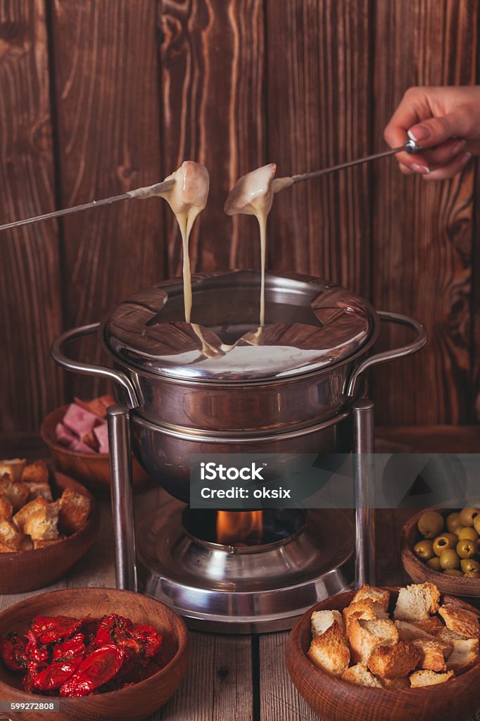 The cheese fondue Delicious Cheese Fondue on a fork on a wooden stand Alcohol - Drink Stock Photo