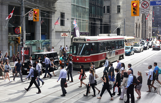Toronto, Canada - August 15, 2016: People Crossing King Street at Yonge, Downtown Toronto, Ontario, Canada. Streetcar and pedestrians during afternoon rush hour in the Financial District, Downtown West neighbourhood. 