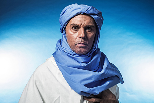 Berber man wearing blue turban with white robe. Studio shot.